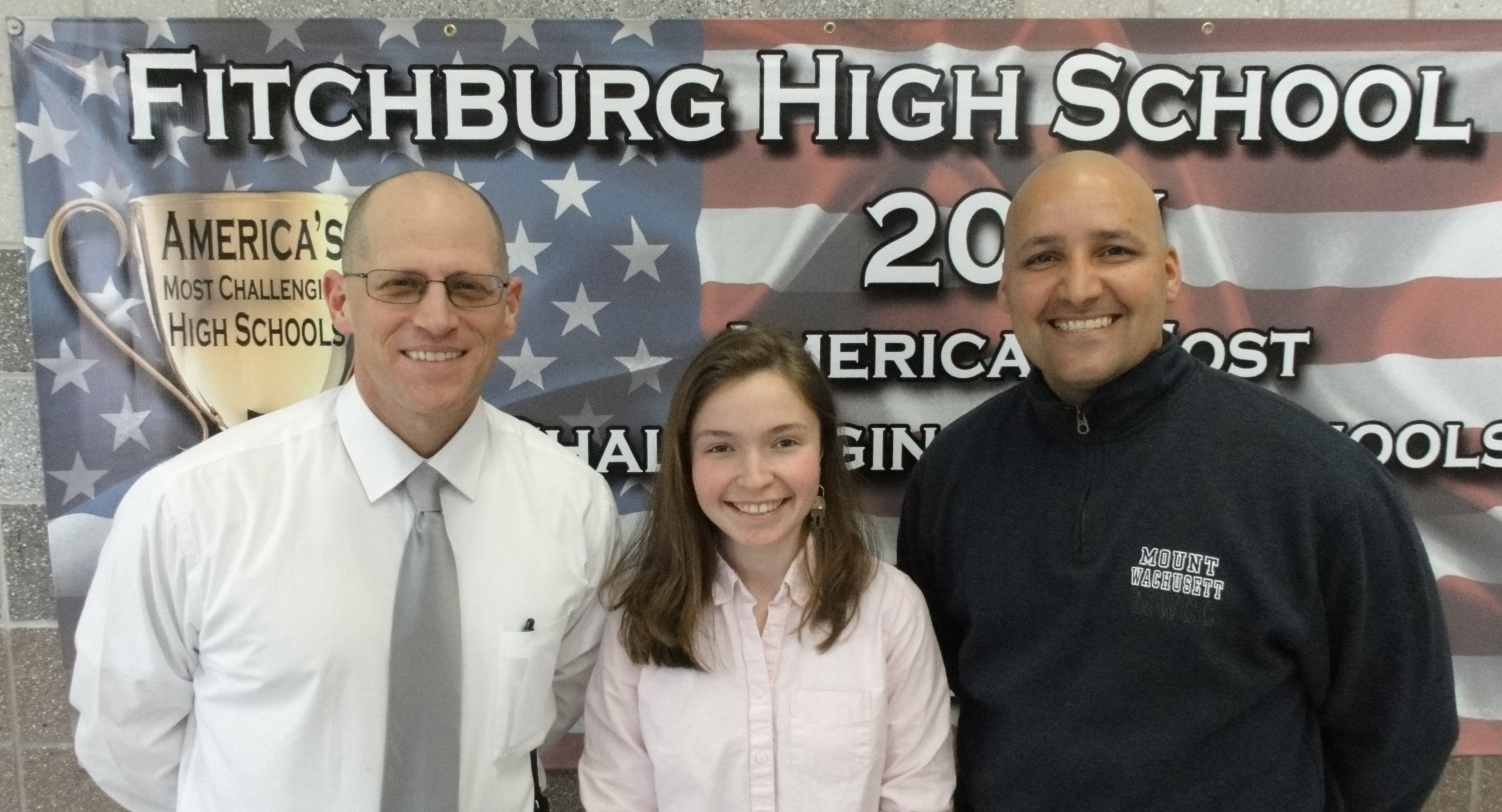 Fitchburg High School Principal Jeremy Roche, left, and Victor Rojas, Assistant Director of the GEAR UP program, right, with scholar Elizabeth Moison