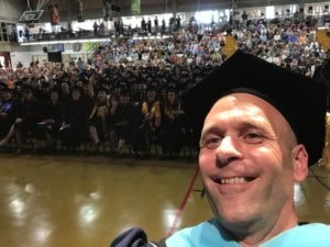 President Vander Hooven taking a selfie from the stage in front of the graduates