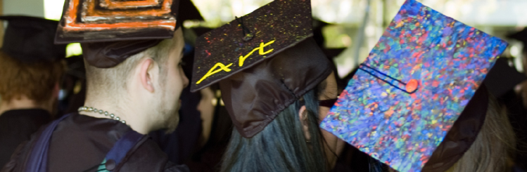 The back of three MWCC Art graduates with decorated mortar boards