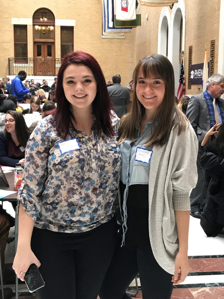 Two female students stand next to each other.