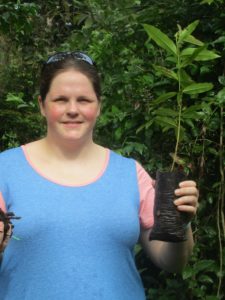 Cristen Comptois is pictured holding a small plant prepared for planting.