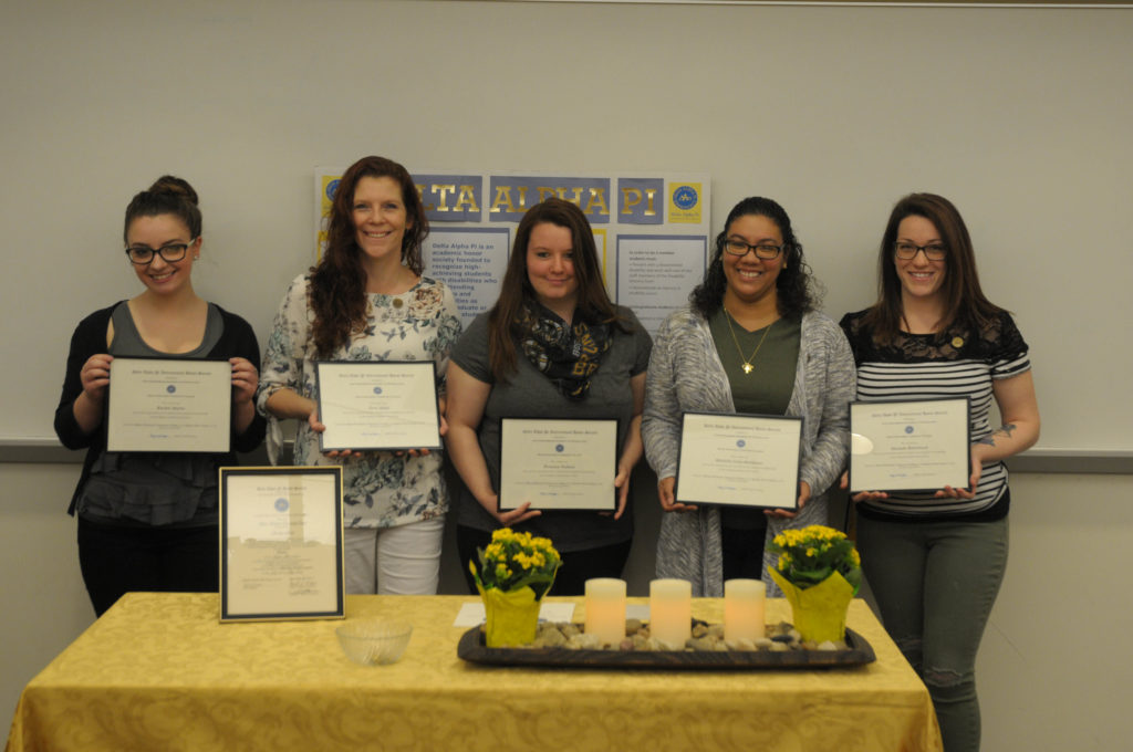 Five female students stand in a row holding certificates.