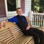 Jonathan Blouin sitting on a bench on a porch