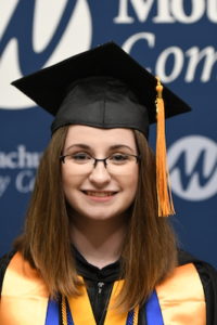 A female student is pictured in her cap and gown from the shoulders up.