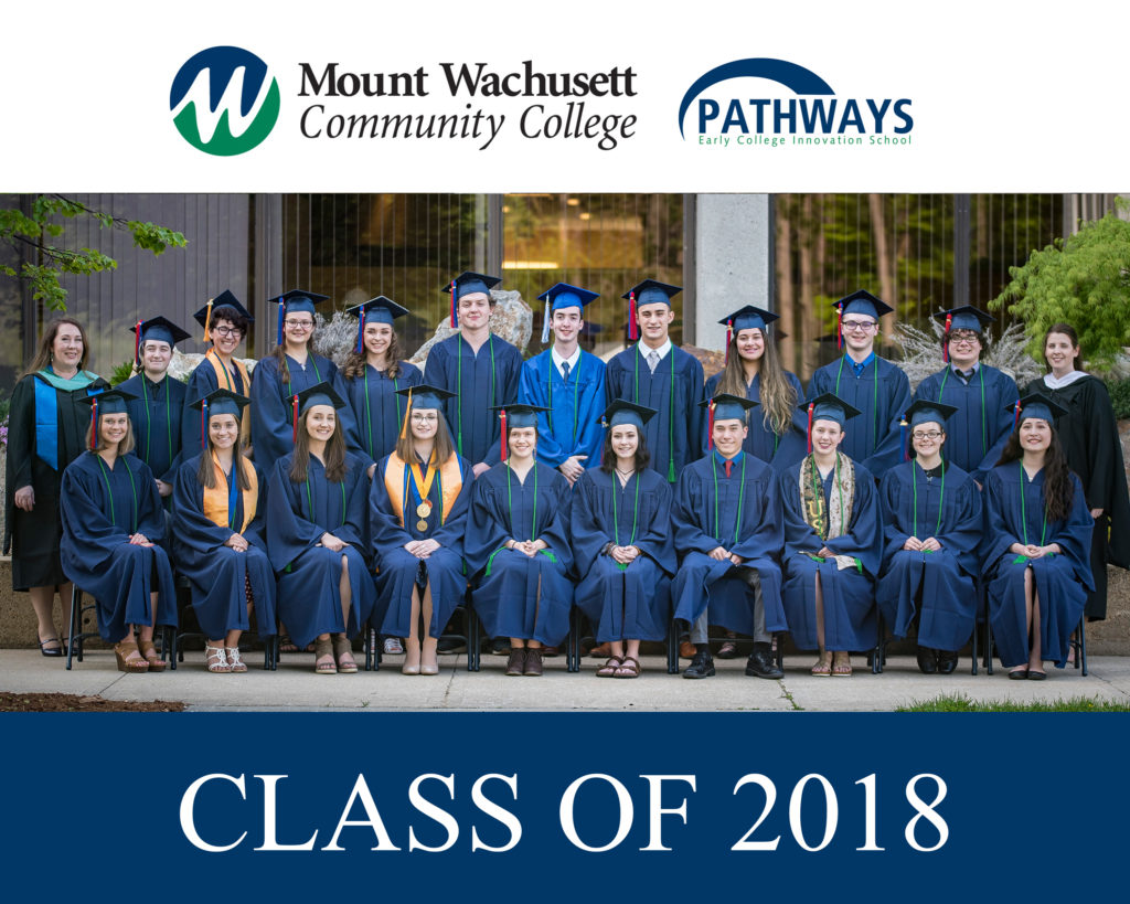 A group of students dressed in graduation cap and gowns is lined up for a photo.