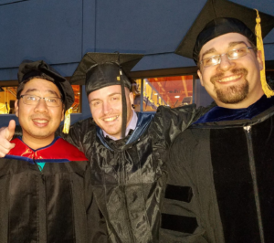 Sunny, Peter G. and Peter O. posing together in their graduation regalia