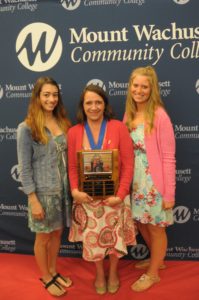 Three women line up holding a plaque.