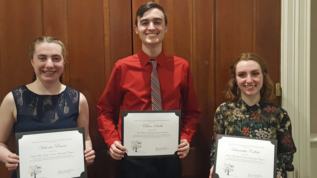 Three students stand in a row holding certificates.