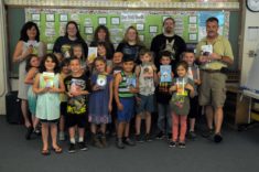 A group of adults stand with first graders.