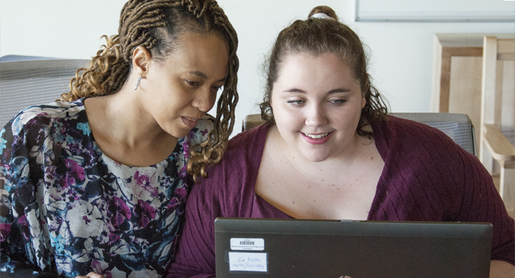 Female advisor with student looking at a laptop