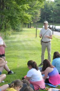 A man stands outside speaking to a group of students.