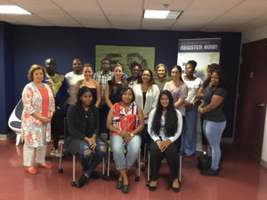 A group of students stands with a professor in a hallway.