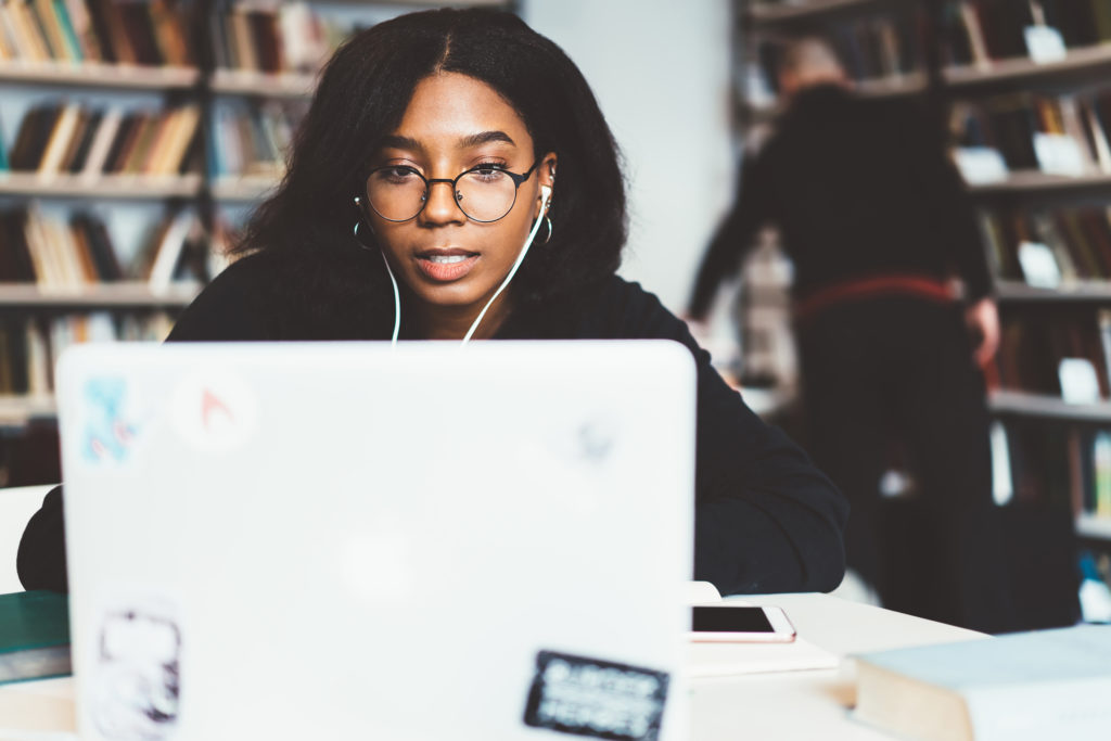 Female student looking at a laptop with headphones