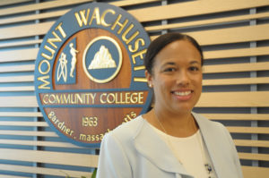 Jamy Gaynor poses in front of the MWCC seal.