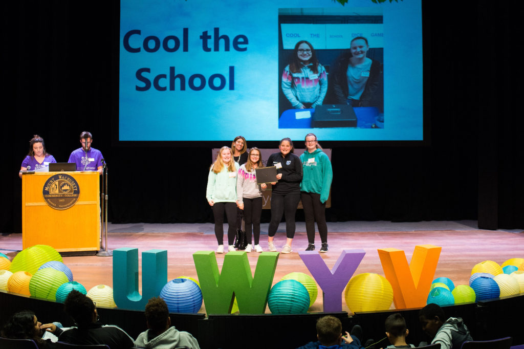 Five people stand on a stage.