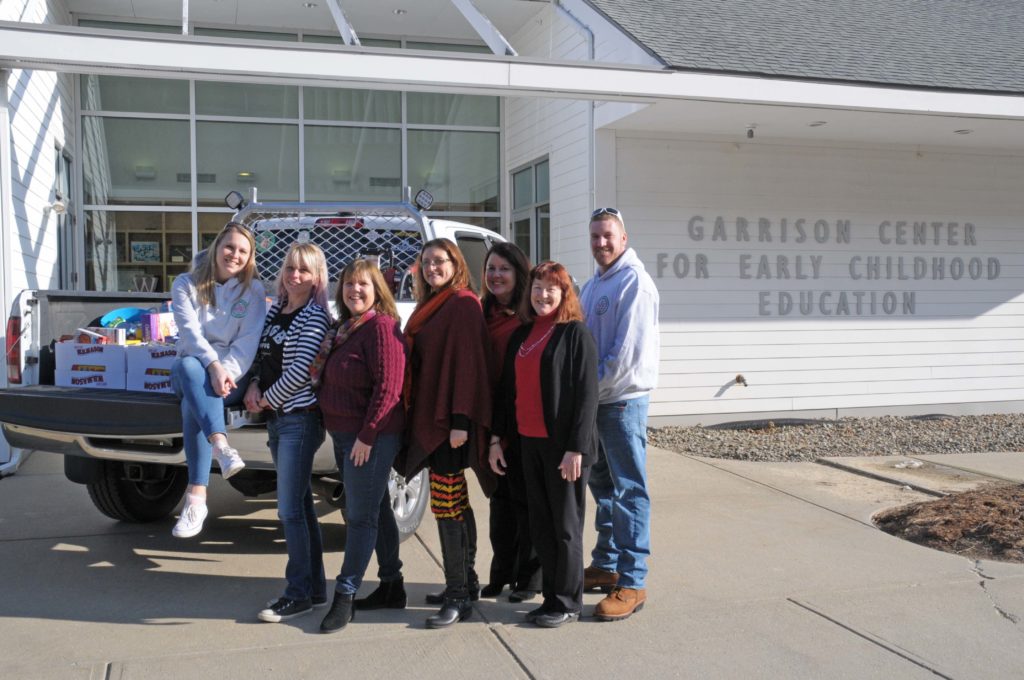 A group of people stand next to a truck outside of a building.