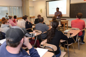 A person stands in front of a classroom of students.