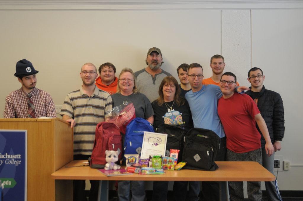 A group of people stand in front of backpacks.