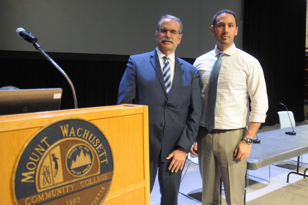 Two men stand together next to a podium.