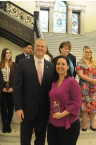 Two people stand together while one holds a plaque.