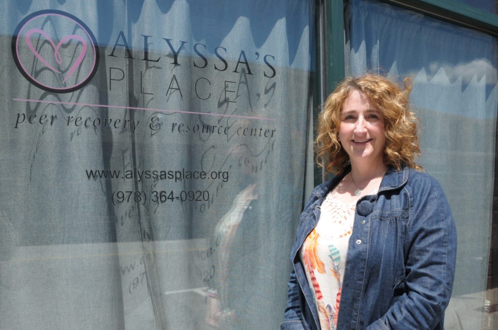 A woman stands in front of the window of a storefront.