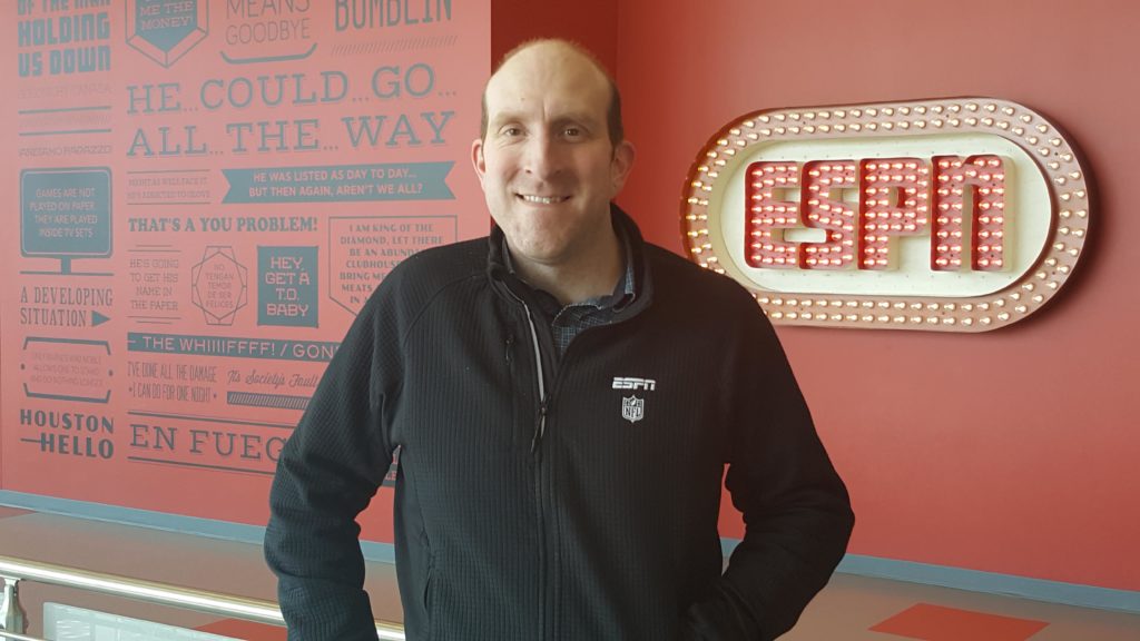 A man stands in front of an ESPN sign.