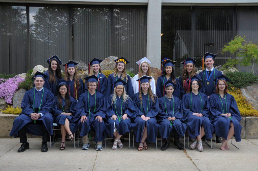 A group of students stands in graduation outfits.