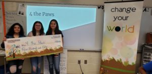 3 girls stand to the side holding a giant check