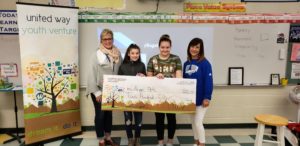 2 kids stand with 2 adults holding a giant check