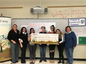 4 teens and 3 adults hold a giant check