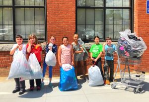 7 kids stand outside holding trash bags