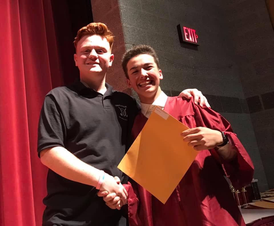 2 students stand together, one is holding a certificate