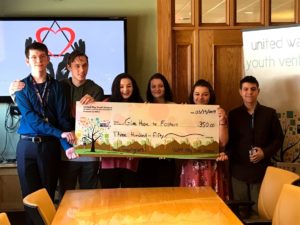 6 teens stand holding a giant check