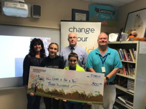 2 kids and 3 adults stand behind a giant check