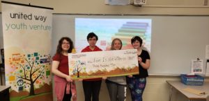 4 kids stand holding a giant check