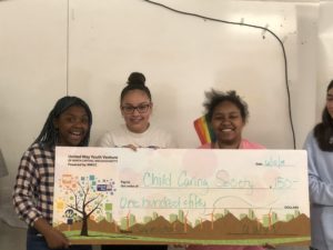 3 kids stand behind a giant check