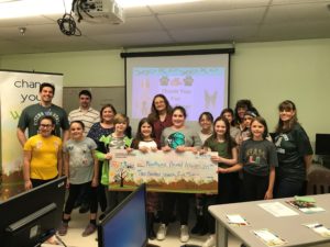 10 kids and 6 adults stand behind a giant check