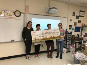 4 teens stand behind a giant check