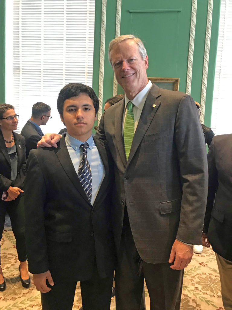 A student stands next to Governor Charlie Baker.