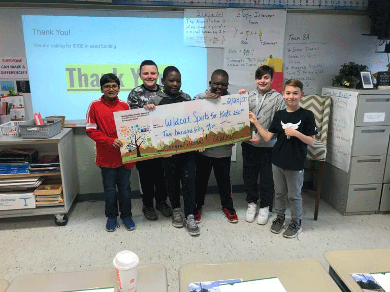 group of boys standing holding large check