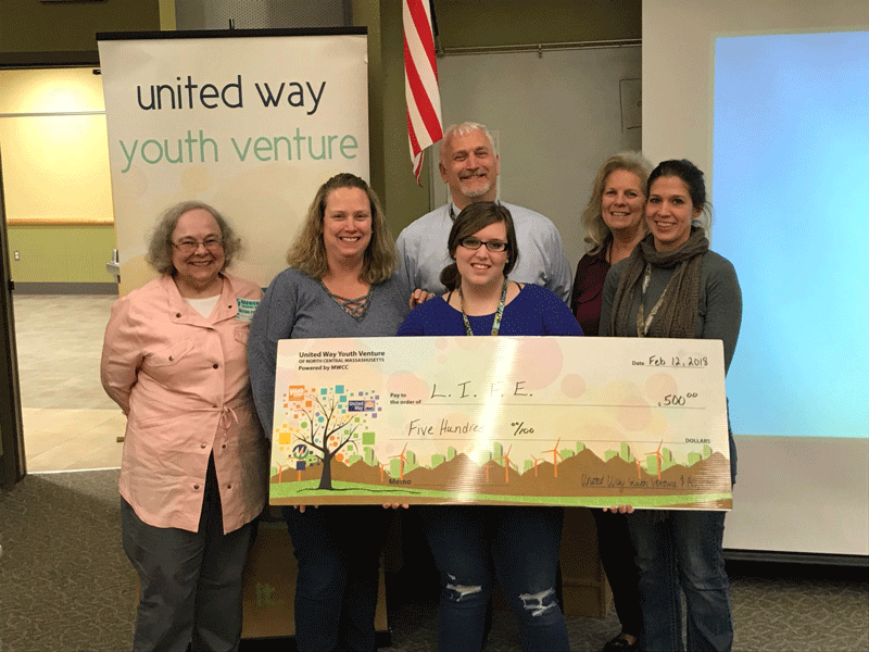 group of adults and one student holding a big check