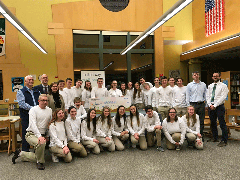 large group of students and adults holding a big check