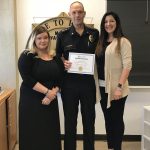 Three people hold up a certificate.