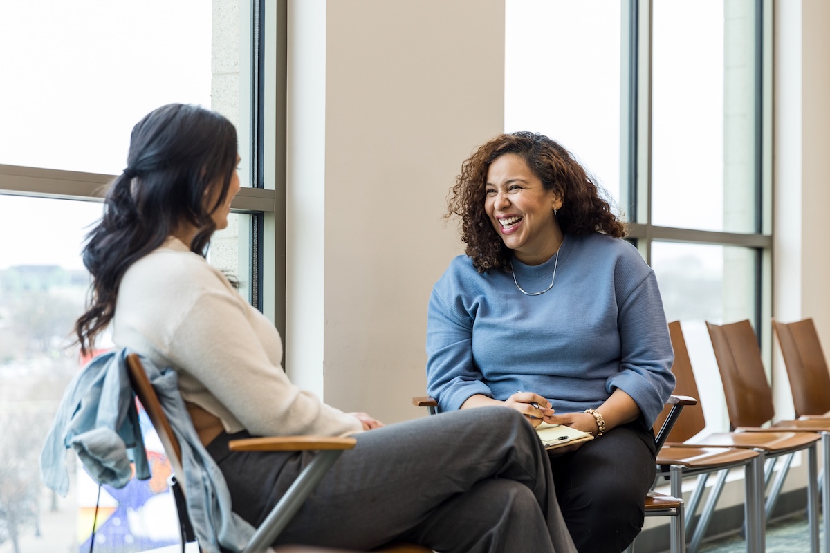 Female therapist shares laugh with unrecognizable female client
