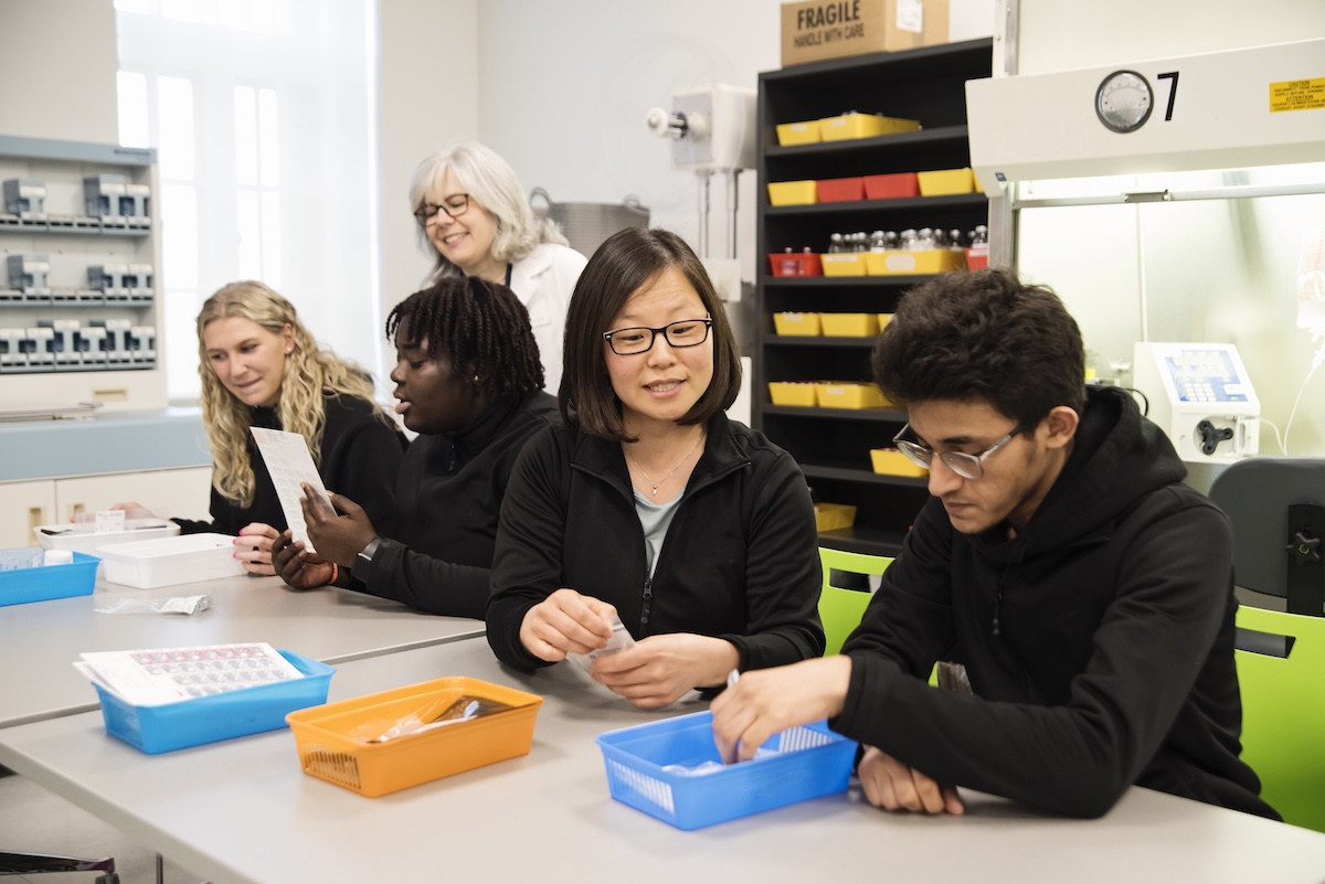 Team of diverse college students with professor in pharmacy studies.