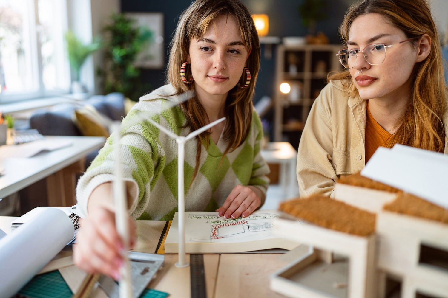 Two female architecture students making architectural model of a modern house