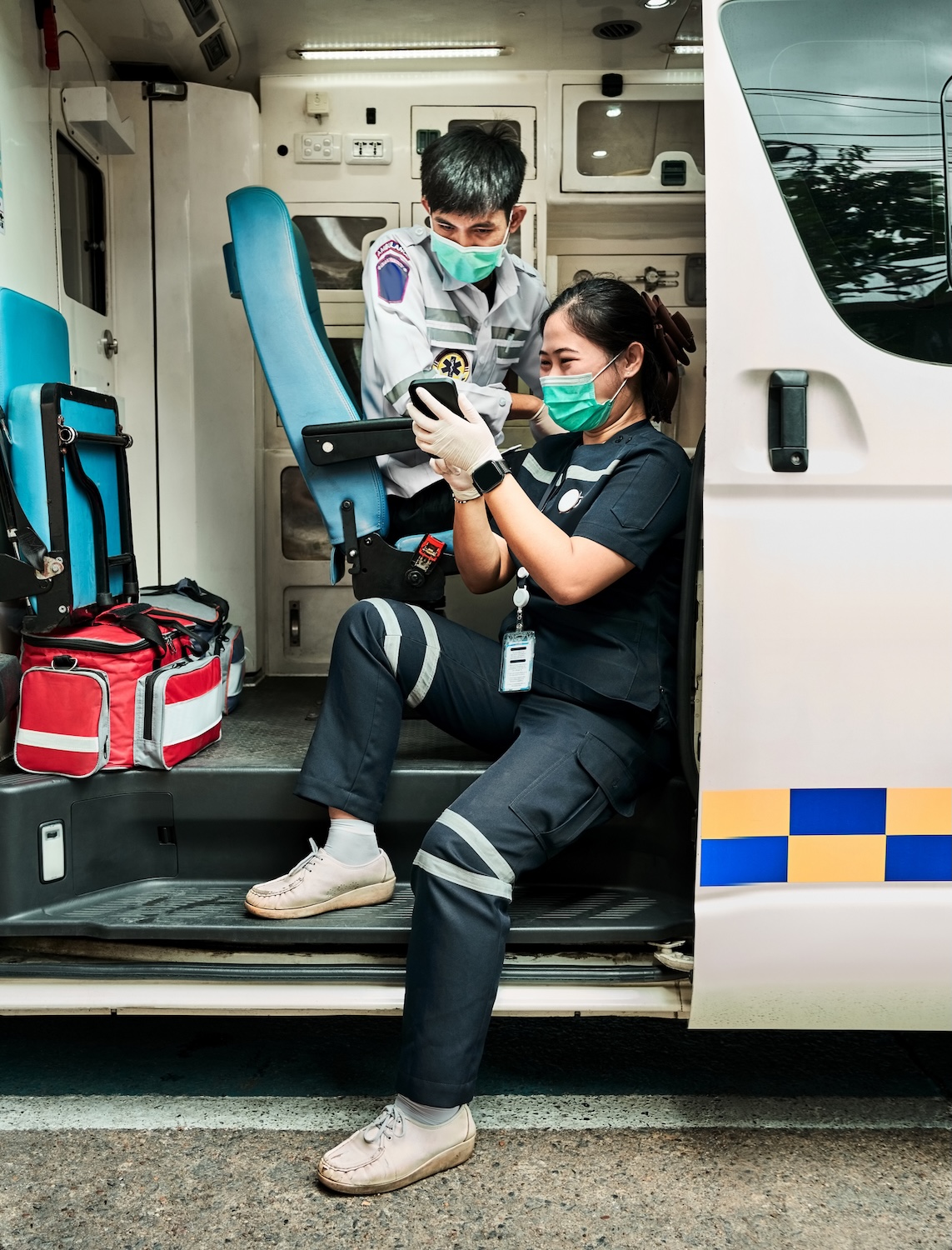Paramedics on break in the ambulance using mobile phone
