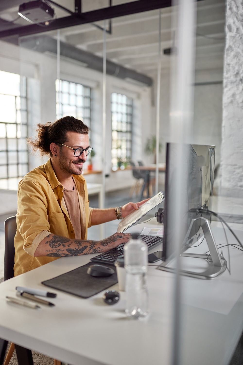 Happy businessman working on reports and PC at corporate office.