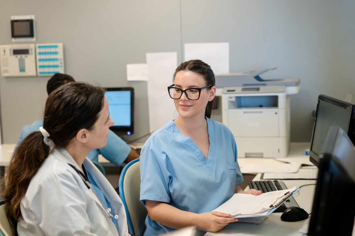 Doctor and administrative worker reviewing a report on a clipboard at the hospital counter