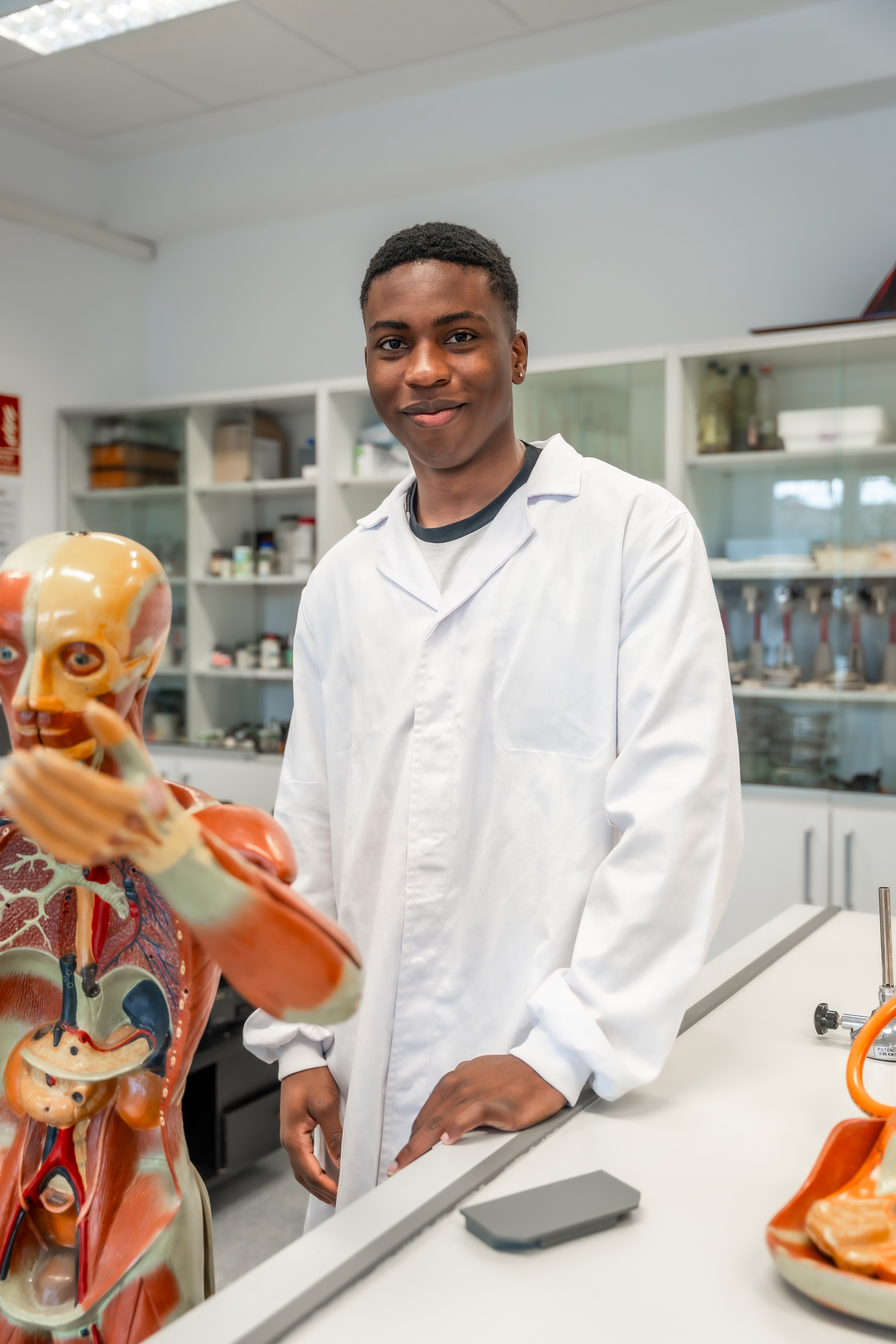 Young male scientist smiling in university laboratory with anatomical model